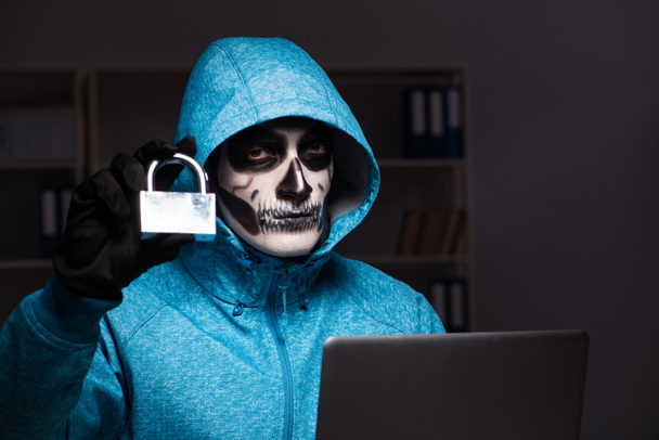 Scary hacker hacking security firewall late in office - Foto, imagen