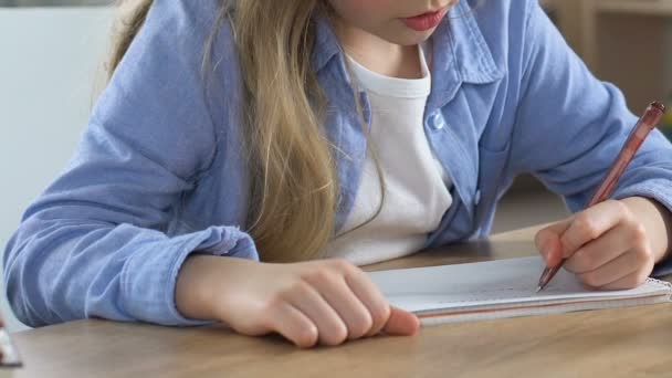 Concentrated school girl doing homework exercise in notebook, home schooling - Metraje, vídeo
