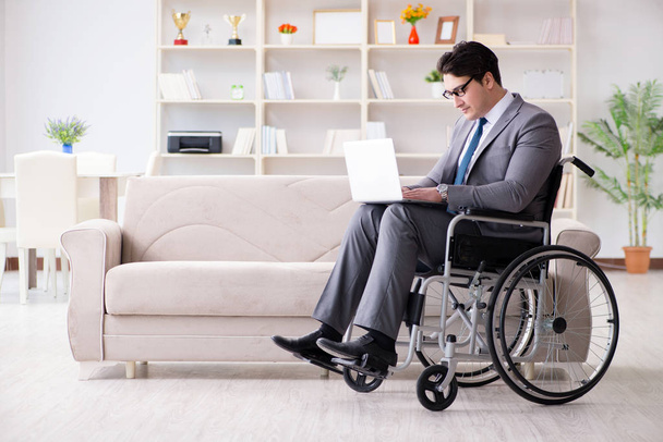 Деловой человек на инвалидной коляске работает дома - Фото, изображение