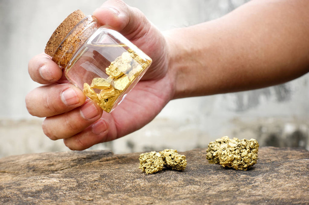 Emberi kéz a lengő palackok, tiszta arany ásványi anyagok bányákban található tartalmazó. - Fotó, kép