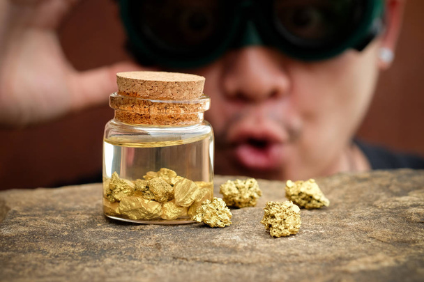 Homem ladrão ser atordoado olhando para o ouro na garrafa com foco seletivo
 - Foto, Imagem