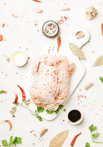 Raw whole chicken with spices and marinade, gray background, top view - 写真・画像