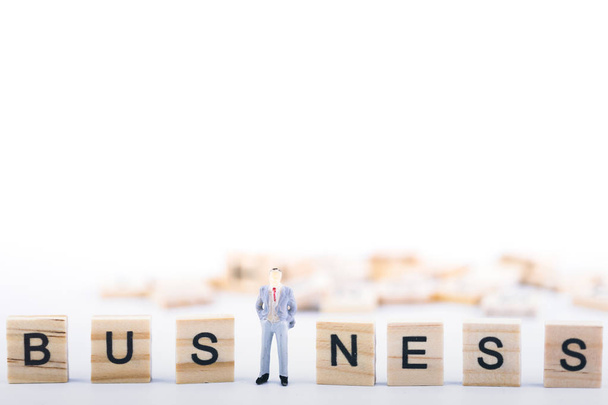 Business leader-concept. Miniatuur mensen kleine figuur staan in de middelste houten kubus met woord bedrijf op witte achtergrond. Met kopie ruimte. Teamwork, Management, zakenman, leiderschap - Foto, afbeelding