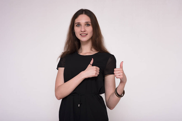 Portrait of a beautiful brunette girl showing ok fingers on a gray background - Fotoğraf, Görsel