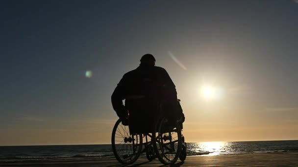 Gehandicapte man over rolstoel motie aan zee kant silhouet Slowmotion - Video