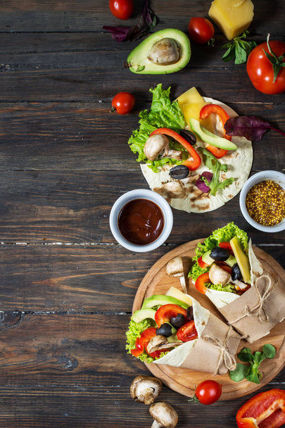 Lanche saudável vegan almoço. Tortilla envolve com cogumelos, legumes frescos e ingredientes em fundo de madeira
. - Foto, Imagem