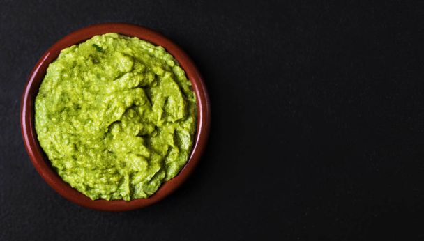 Mexican food guacamole in clay bowl on black background - Photo, Image