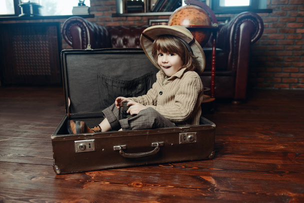 niño se sienta en la maleta
 - Foto, imagen