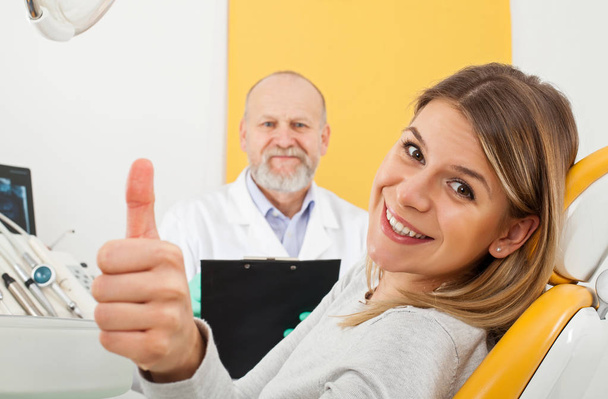 Smiling woman at the dentist office showing thumbs up - Foto, immagini