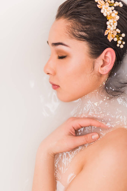 Closeup portrait of a young woman relaxing in the milk water - Foto, Imagen