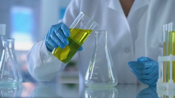 Chemist pouring yellow substance test tube, petrol quality analysis, experiment - Felvétel, videó