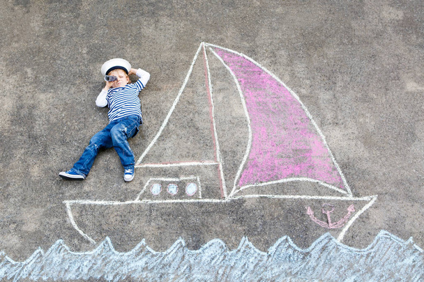 Μικρό παιδί αγόρι ως πειρατής σε πλοίο ή sailingboat ζωγραφική εικόνα με πολύχρωμες κιμωλίες σε άσφαλτο. - Φωτογραφία, εικόνα