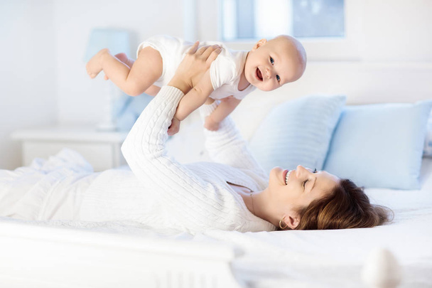 Moeder en baby op een witte bed - Foto, afbeelding