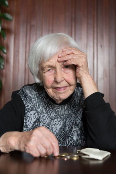 Donna anziana seduta al tavolo che conta i soldi nel portafoglio
. - Foto, immagini