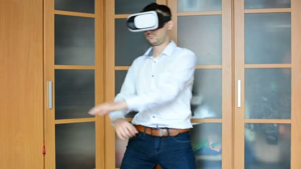 Uomo con le cuffie VR in salotto. Usare i gesti con le mani
. - Filmati, video
