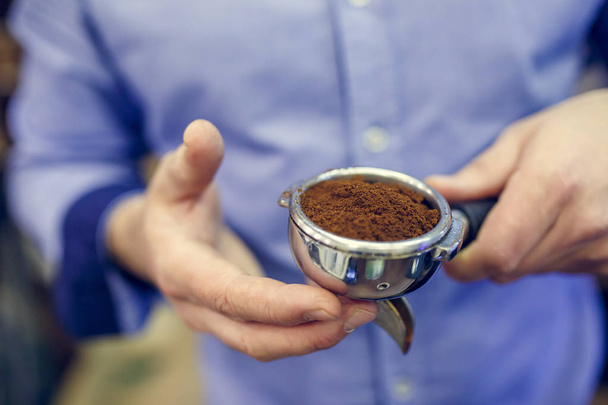 Photo of barista man with ground coffee in hands - Zdjęcie, obraz