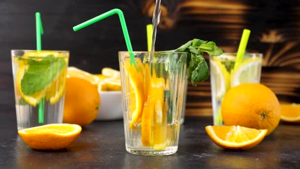 Наливание воды в стакан со свежими срезанными ломтиками апельсинов
 - Кадры, видео