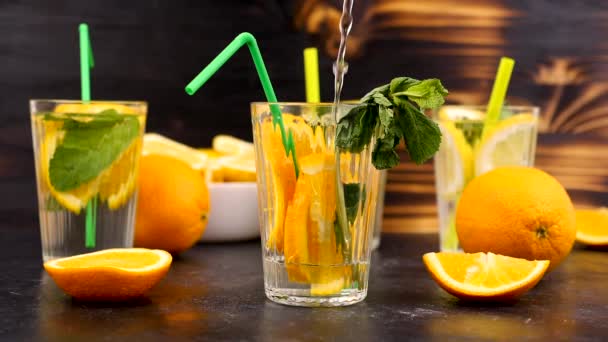 Gieten van water in een glas met plakjes van sinaasappelen - Video