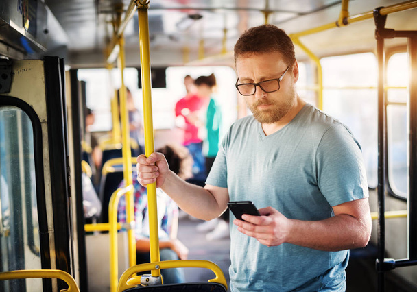 joven hombre guapo de pie en el autobús y el uso de teléfono móvil
 - Foto, imagen