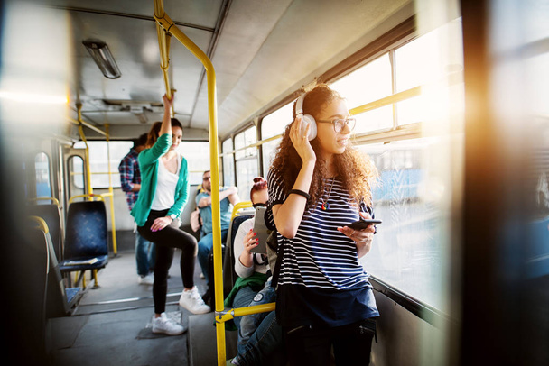 молодая красивая женщина слушает музыку в наушниках в автобусе
 - Фото, изображение