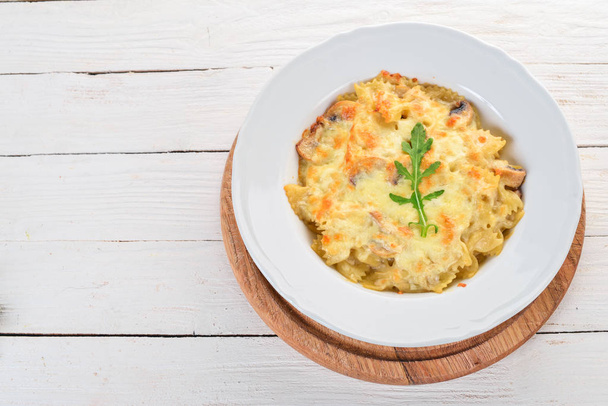 Farfalle pasta with cheese and mushrooms. On a wooden background. Top view. Copy space. - Foto, Imagem