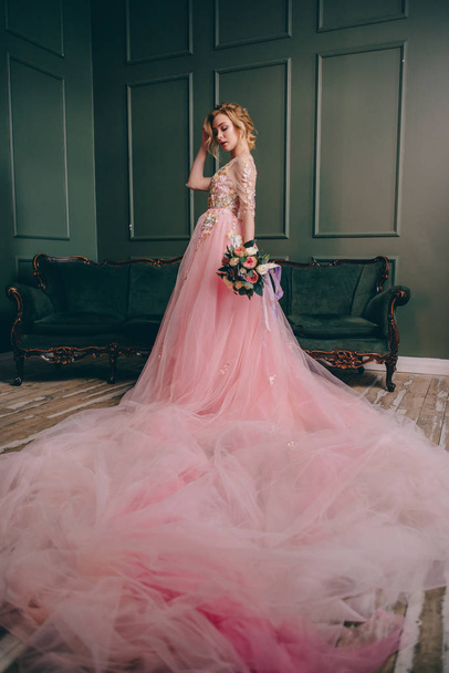 young beautiful woman in a pink dress standing in a vintage room - Foto, Imagen