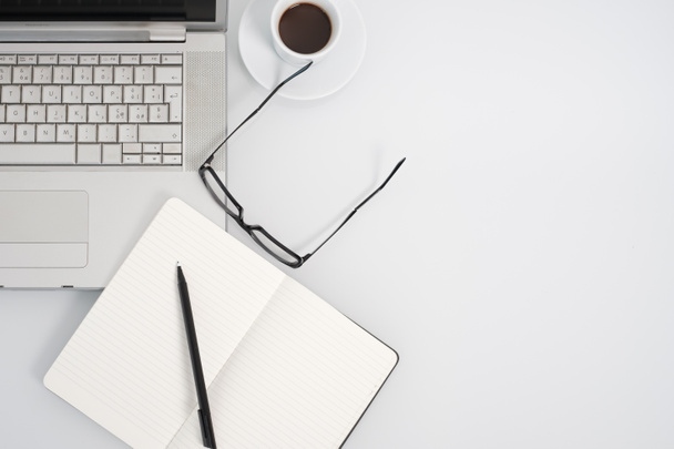 Modern munkaterület szóközzel kávé-kupa, notebook és másol a háttér fehér színű. Szemközti nézet. - Fotó, kép