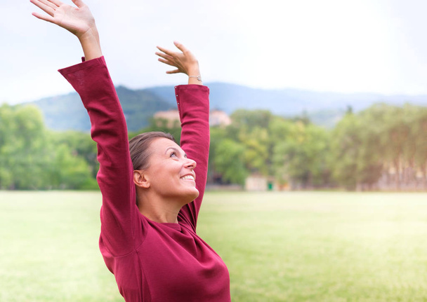 Portrait d'une femme excitée avec les yeux ouverts levant les bras vers le ciel à l'extérieur
 - Photo, image