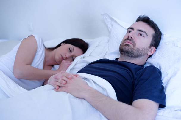 Sad and depressed man lying in the bed with wife - Foto, immagini