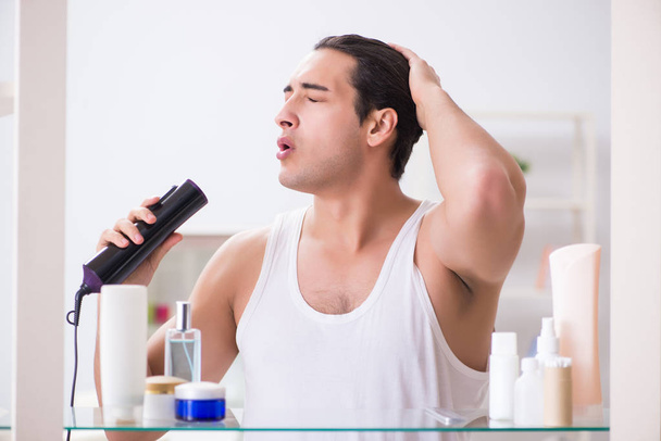 Nuori mies kuivattaa hiuksiaan aamulla - Valokuva, kuva