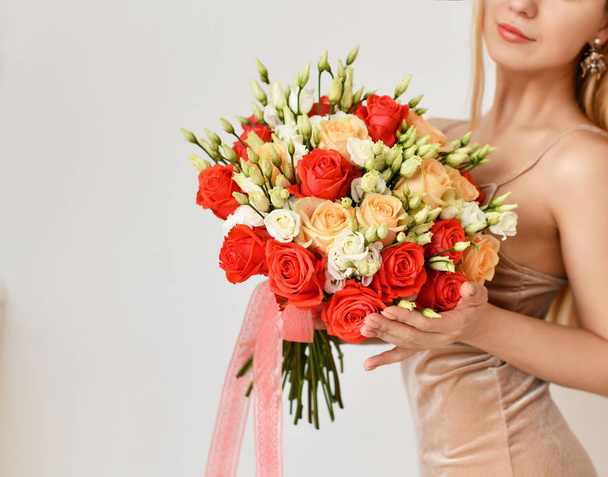 Красива жінка тримає букет з червоних і рожевих троянд квіти щасливі посміхаючись на сірому
  - Фото, зображення
