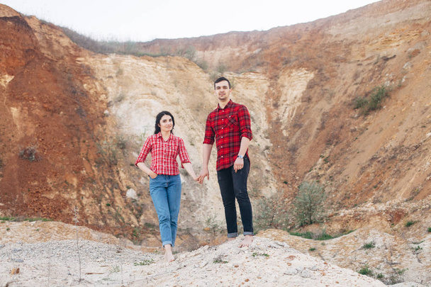 Прекрасная пара в красных клетчатых рубашках, стоящих в песчаном каньоне или ква
 - Фото, изображение