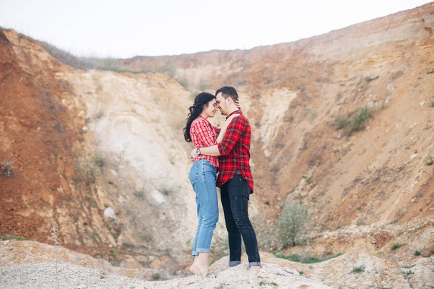 Lovely couple in red plaid shirts standing and embrace in sand c - Foto, immagini