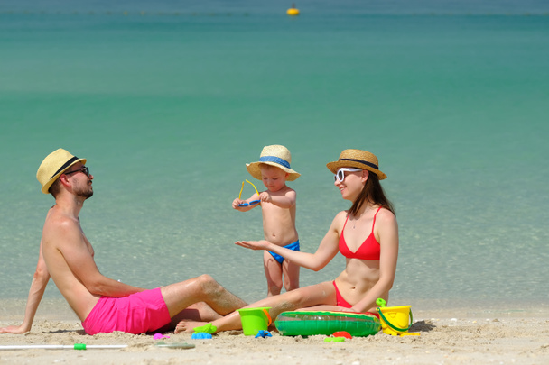 Család a parton. Két éves kisfiú játszik a strandon anyával és apával a strandon.. - Fotó, kép