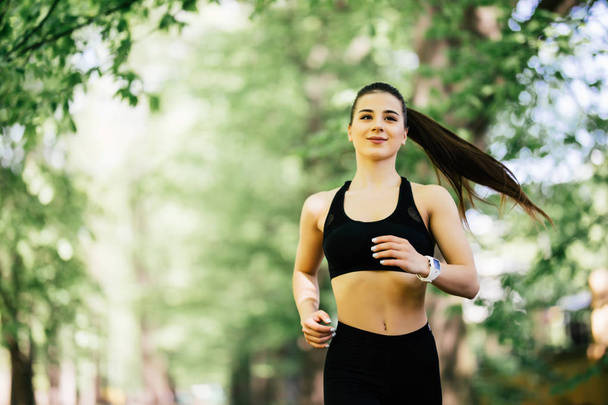Молода усміхнена спортивна жінка біжить у парку. Фітнес дівчина біжить в парку
 - Фото, зображення
