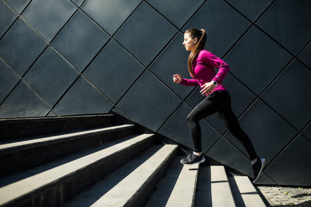 Mujer atlética corriendo escaleras arriba durante cardio. entrenamiento de intervalos
 - Foto, imagen