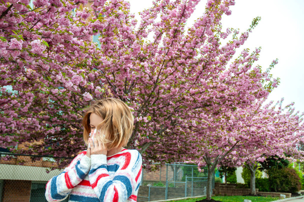 Spring allergy.  Woman blowing near spring tree in bloom. - Foto, Imagen