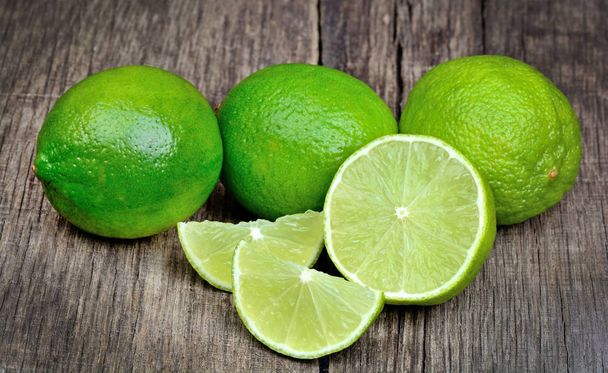 Lime slice and green limes on wooden background - Photo, Image