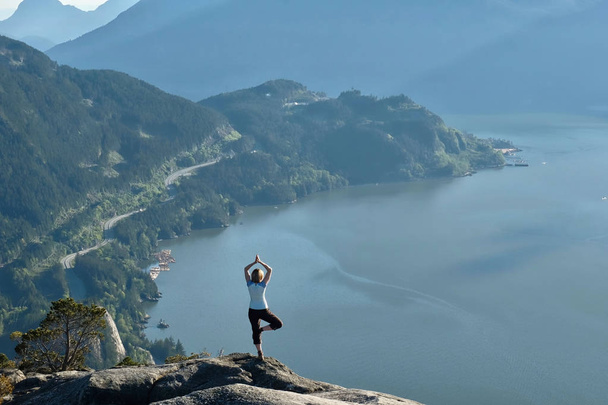 Woman meditating on mountain top above the ocean.  - Photo, Image