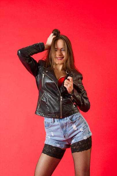 Portrait of a girl in a leather jacket and denim shorts. - 写真・画像