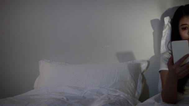 Азіатські жінки за допомогою смарт-телефону на ліжко, перш ніж вона спати по ночах. Концепція мобільних наркоман. Змішана раса азіатських китайські моделі - Кадри, відео