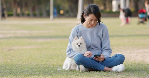 屋外の公園で彼女のポメラニアン犬と遊ぶ女性 - 写真・画像