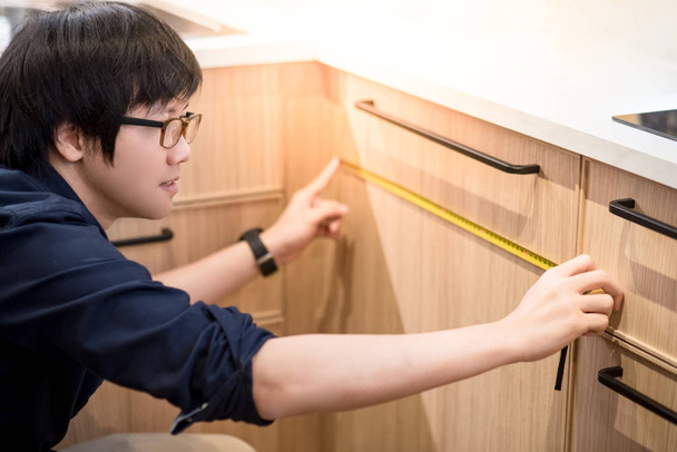 Юнак азіатських за допомогою рулеткою для вимірювання меблі - Фото, зображення
