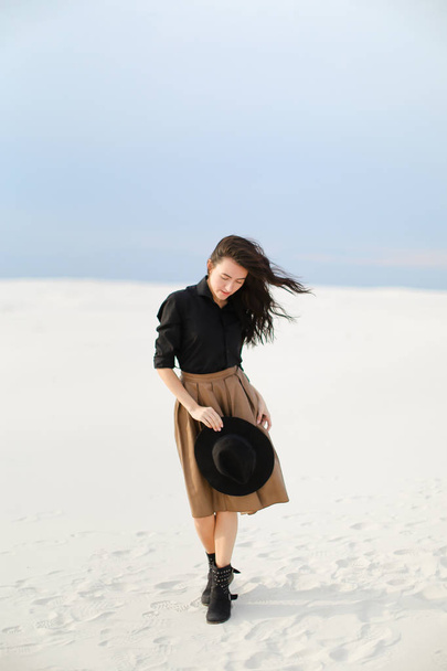 Caucasian lady wearing skirt, black blouse with hat and standing on snow. - Foto, imagen