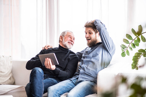 Hipster son and his senior father with tablet at home. - Photo, image