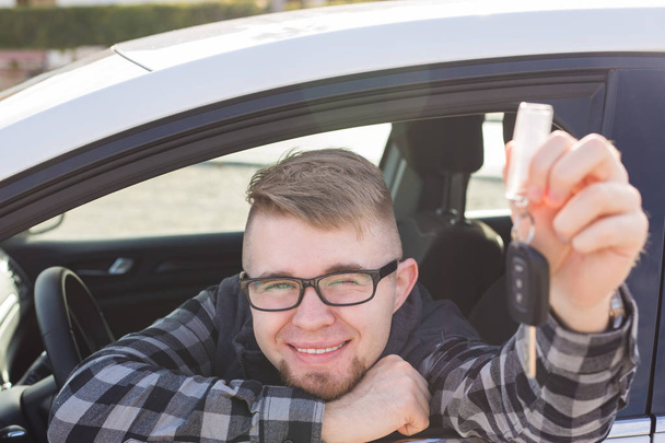 Νεαρός άνδρας κρατά το κλειδί στο άσπρο αυτοκίνητο - Φωτογραφία, εικόνα