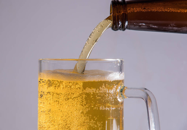 Beer in a glass poured from a bottle thrown from the ice and foam - Фото, изображение