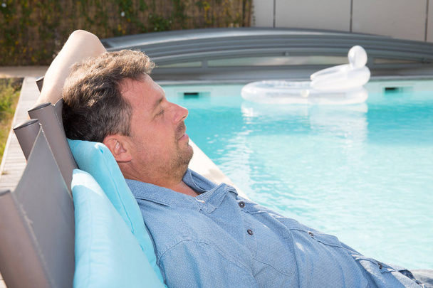 ontspanning knappe man slleeping in zwembad home zomer - Foto, afbeelding