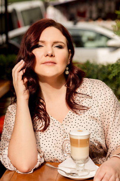 Mulher madura bonita sentada em um café de rua com uma xícara de co
 - Foto, Imagem