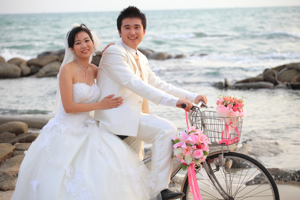 Couple of young man and woman in wedding suit ridiing old bicycle - Photo, Image